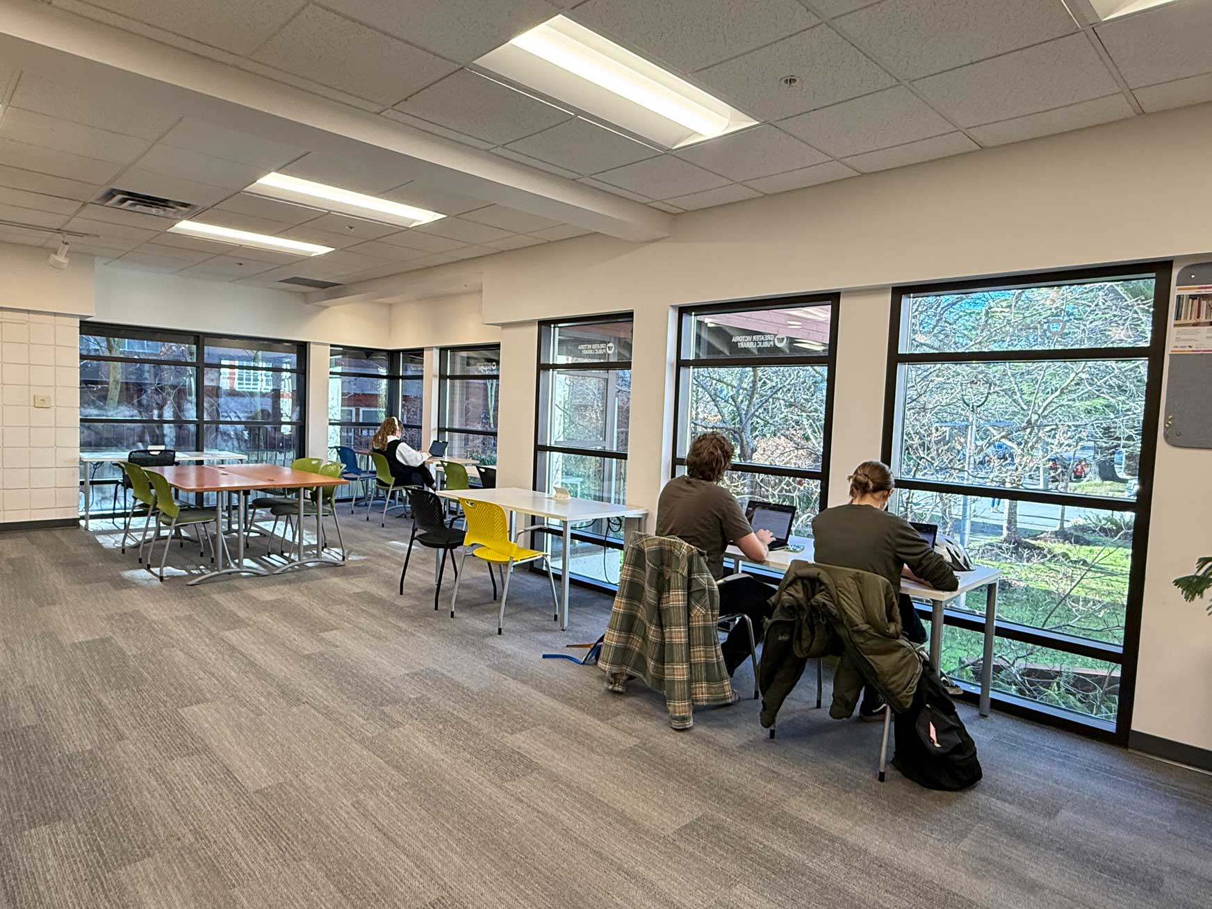 Oak Bay branch interior showing windows with tables by them and people working on laptops