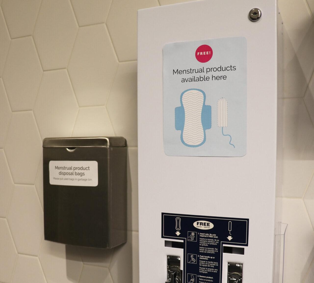 A menstrual products dispenser installed in a public restroom, offering pads and tampons to support menstrual health and accessibility.