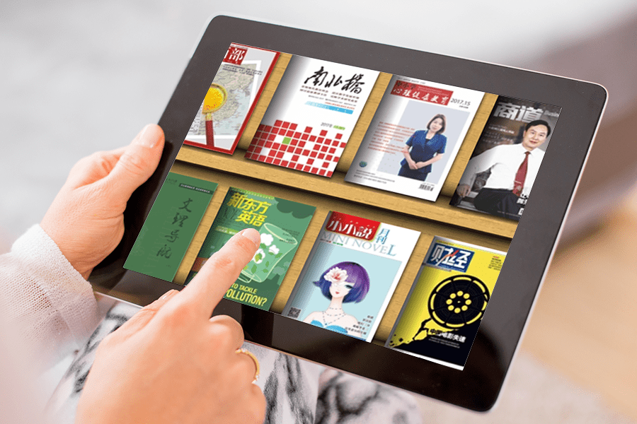 Hands holding tablet with magazine covers in Chinese languages.