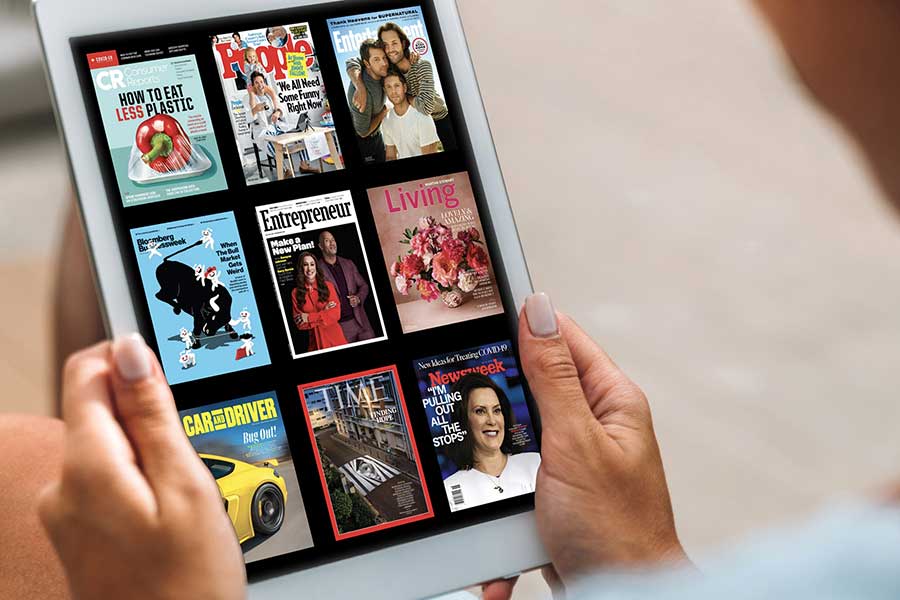 Two hands showing a selection of magazine covers featured on a tablet