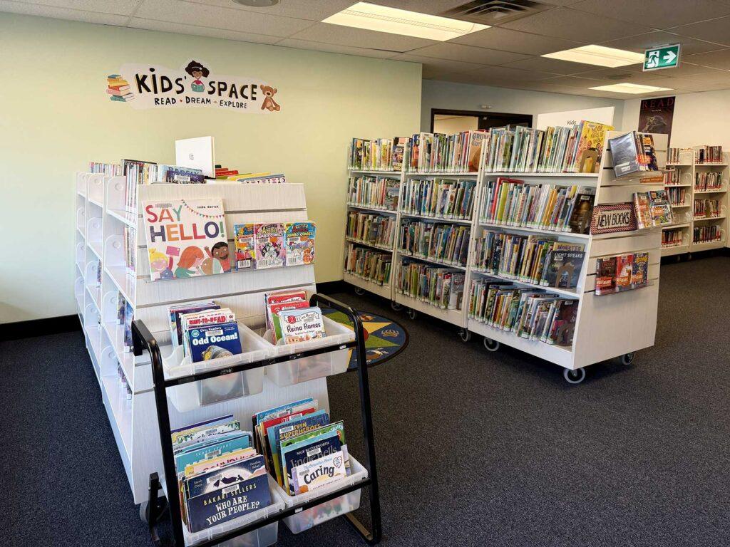 Nellie McClung Express - books stacked on the racks in the children's area. A sign on the wall reads: kids space - read - dream - explore
