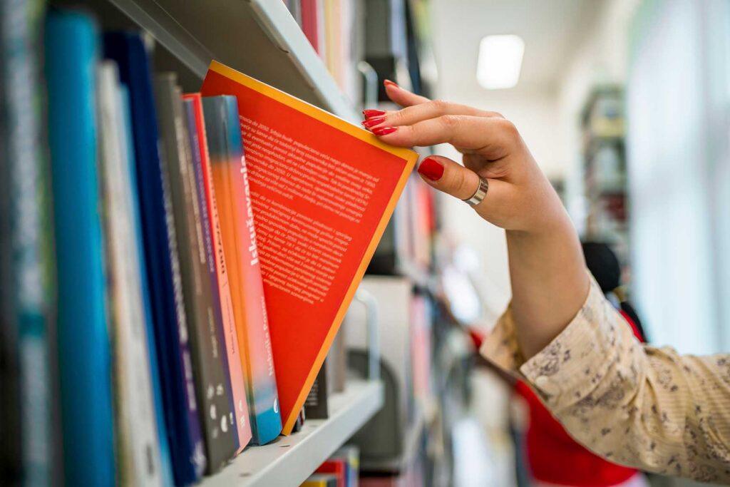 a hand pulls a book from the stacks