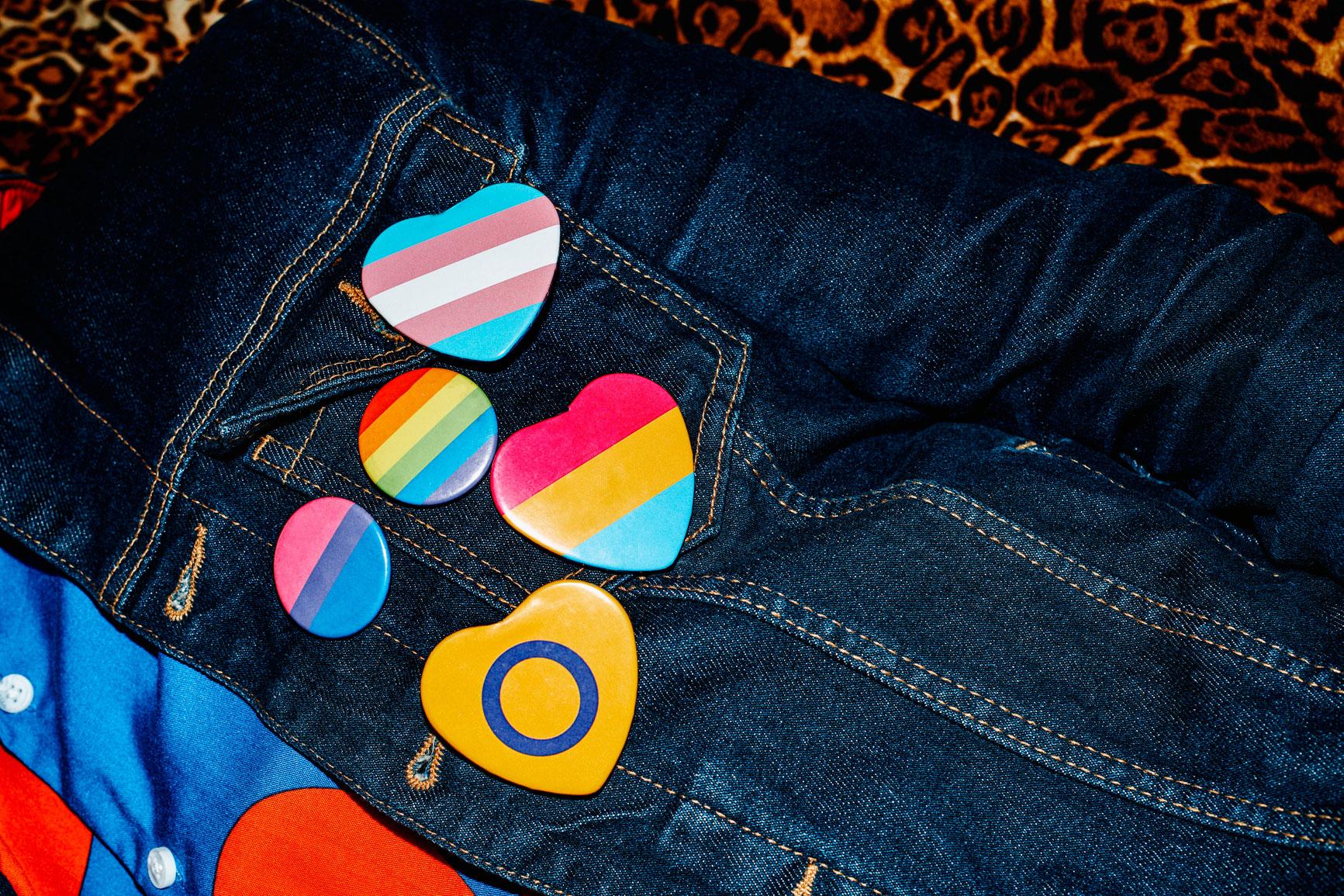 2SLGBTQIA+ colourful badges and pins on a jeans jacket.