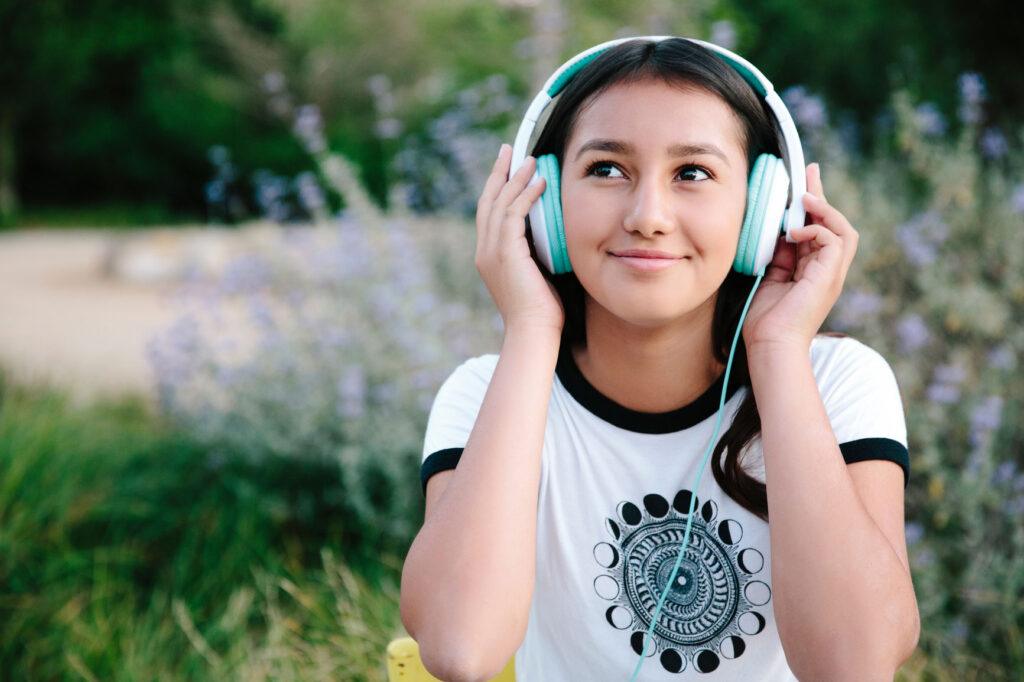 Young girl smiling while listening to her headphones.