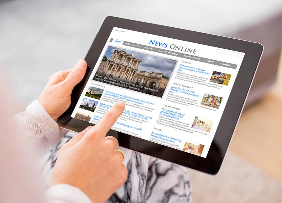 Hands holding a tablet reading the news.