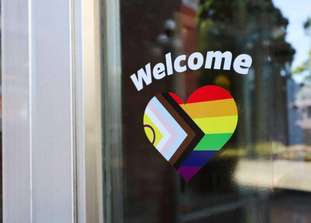 welcome sticker of a heart and pride flag on a window