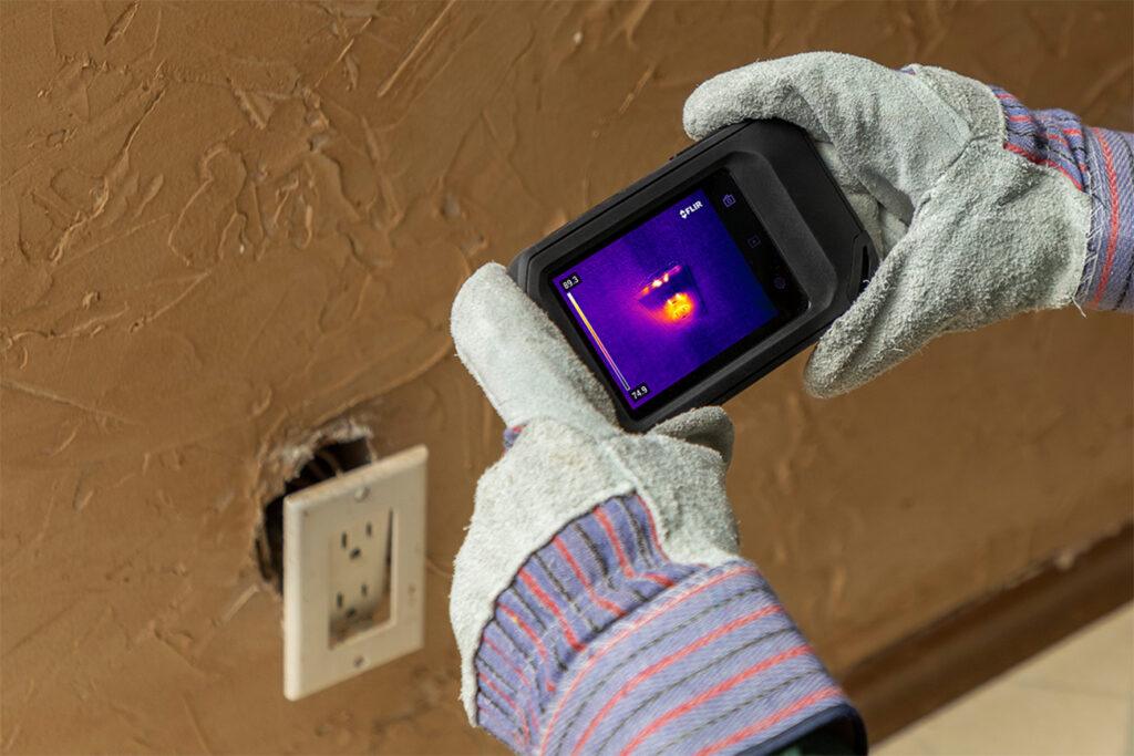 Digital Thermal imaging camera being used against an electrical outlet.